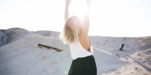 Femme blonde en plein désert qui lÚve les mains vers le ciel